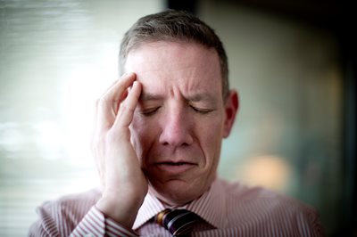 man holding his head with eyes shut