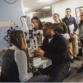 Students using optometry equipment during OLE program in 2019.