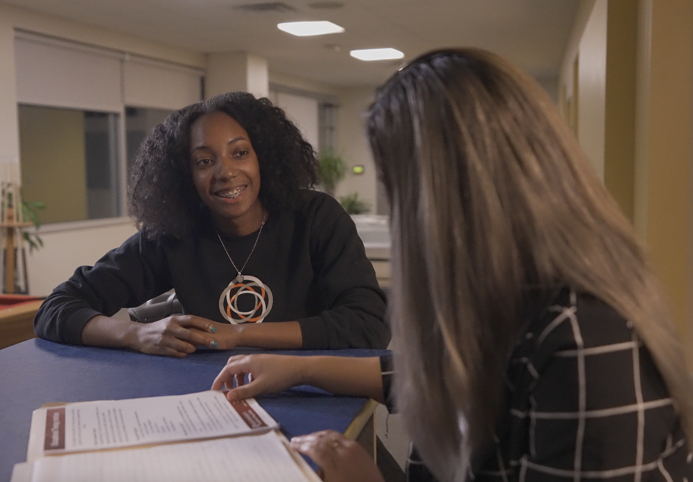 Tavii and Michelle sitting at a table reviewing a document