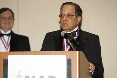 Dr. Satya Verma speaking at a podium