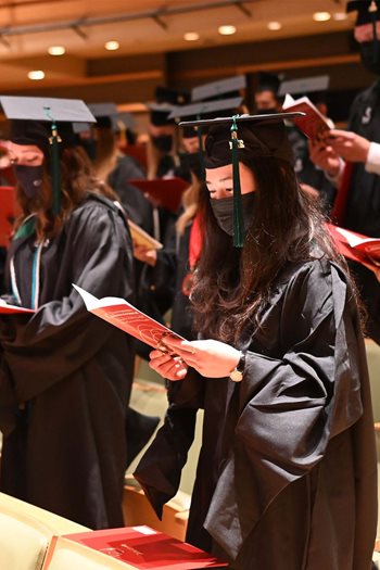 Photo of Salus students during commencement reading the program at the Kimmel Center