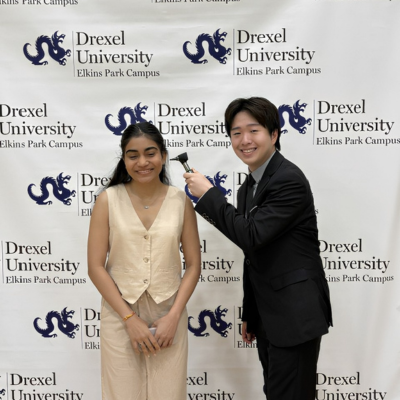 Jason holding an otoscope next to another audiology student's ear