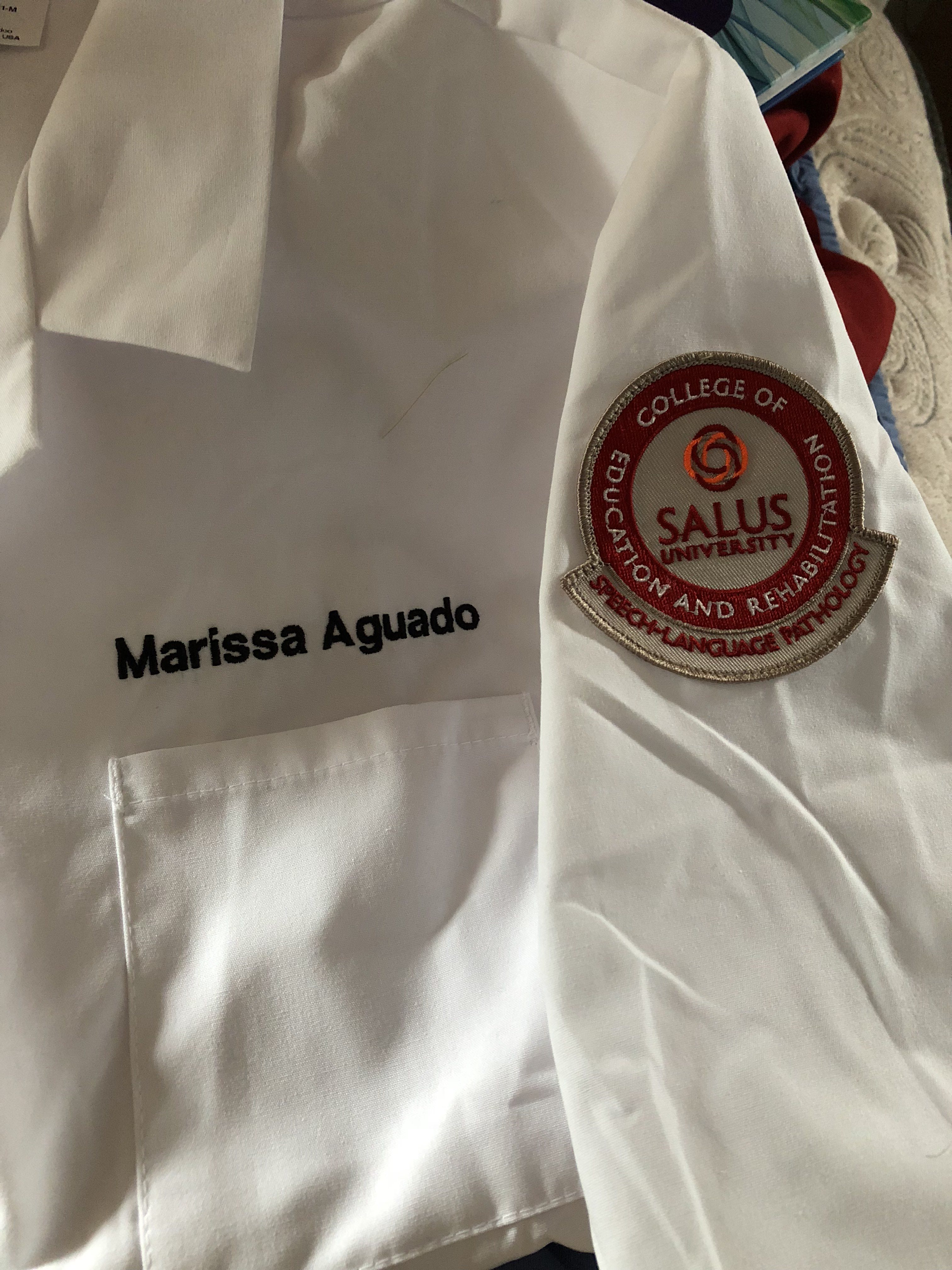 Marissa's white coat with the Salus badge and her name embroidered