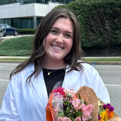 Megan in her white coat holding flowers